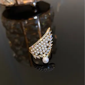 Vista detallada de un anillo de ala de ángel dorado con perlas blancas y circonitas