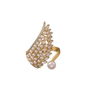 Elegante anillo abierto con forma de ala dorada con perlas y circonitas brillantes