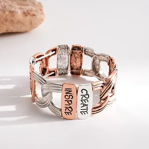 Detailansicht eines zweifarbigen elastischen Metallarmbands mit Inspire-Gravuren