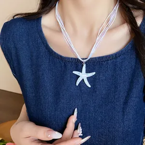 Close-up of a blue resin starfish pendant necklace on multi-strand white ribbon