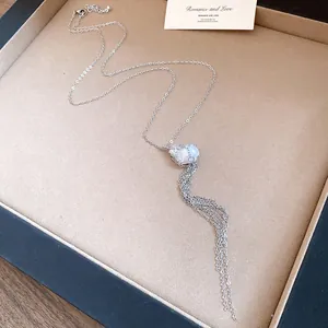 Detail of silver chain necklace featuring a mesh-wrapped baroque pearl with a long tassel.