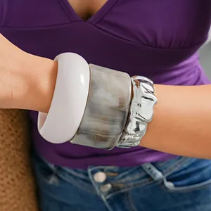 Dettaglio ravvicinato di bracciali in acrilico bianco, effetto marmo e trama stropicciata