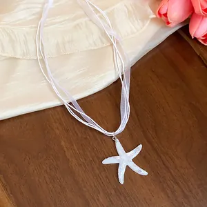 Close-up macro view of the shimmering white resin starfish pendant on ribbon cord