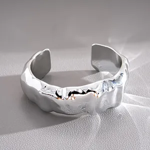 Vista macro dettagliata di un bracciale rigido aperto argento lucido texture stropicciata