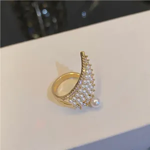 Primer plano detallado de un anillo de ala dorada adornado con perlas blancas y circonitas pavé