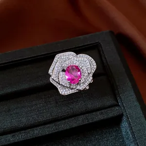 Primo piano di un anello a forma di rosa con gemma rosa e cristalli su scatola di velluto.