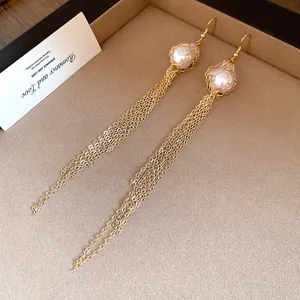 Close-up detail of golden chain tassel earrings featuring elegant mesh-wrapped pearls