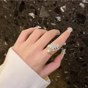 Elegante anillo en forma de ala con perlas y circones lucido en el dedo índice.