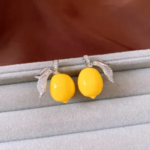 Close-up of vibrant yellow resin lemon jewelry with sparkling zircon leaves