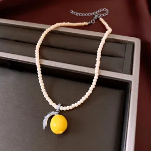 Detailed macro shot of a yellow resin lemon pendant with sparkling zircon leaf