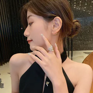 Primer plano de un elegante anillo de ala dorada con circonitas y perla en el dedo