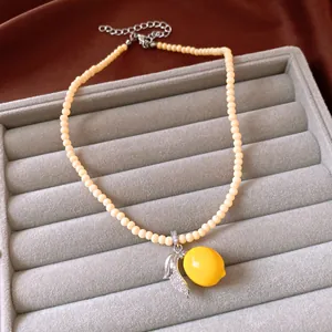 Detailed macro shot of vintage lemon pendant necklace with resin beads on velvet tray