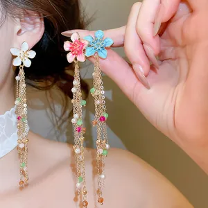 Detailed macro shot of oil-dripped flower tassel earrings with pearls and beads on model