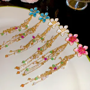 Detailed view of colorful enamel flower tassel earrings in blue, white, and pink styles.