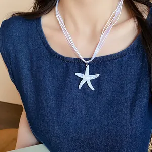Close-up detail of white resin starfish pendant on a delicate ribbon choker necklace