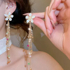 Close-up of elegant white enamel flower tassel earrings with pearls and beads