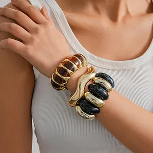 Detailed close-up of chunky marbled acrylic and gold-tone geometric bangles