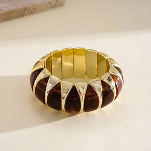 Close-up macro detail of a chunky geometric acrylic bracelet with gold accents and amber dye