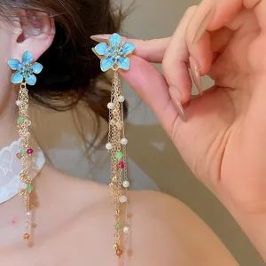 Detail of blue enamel flower tassel earrings with colorful bead accents and long chains.