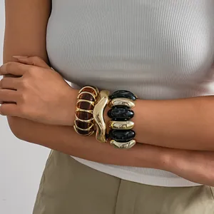 Close-up detail of chunky geometric bracelets with marbled acrylic and gold-tone finish