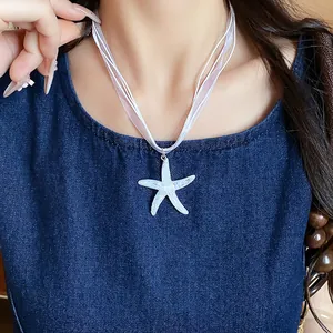 Close-up of a white resin starfish pendant necklace on a multi-strand ribbon cord