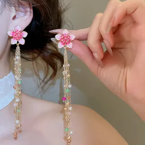 Close-up of pink flower tassel earrings with pearls and beads for a sweet vacation look.