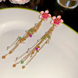 Close-up of pink enamel flower tassel earrings with pearls for a summer vacation look