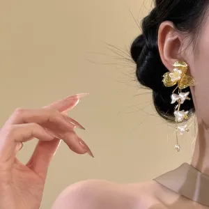 Close-up detail of French vintage style golden flower tassel earrings worn by a model