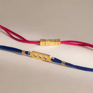 Dettaglio di braccialetti in corda colorata con cubi LOVE e ritagli a cuore