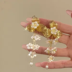 Close-up detail of elegant French retro gold and white floral tassel drop earrings