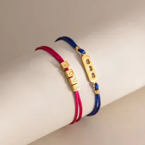 Dettaglio di bracciali intrecciati colorati con perline 'LOVE' dorate e ciondoli a cuore