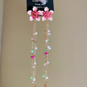 Detailed view of elegant pink enamel flower tassel earrings featuring pearls and beads.