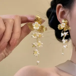 Close-up of elegant French retro gold flower tassel earrings with white blossoms