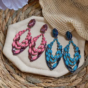 Detailed view of pink and blue boho chandelier earrings with enamel leaves and rhinestones.
