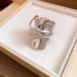 Primo piano di un anello d'argento ondulato irregolare in una scatola regalo color crema.