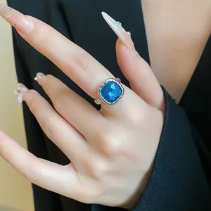 Primo piano di un anello d'argento con una gemma blu quadrata indossata al dito