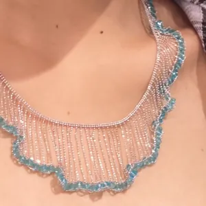 Detail of French style silver lace fringe necklace with delicate blue beads.