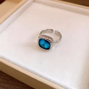 Dettaglio ravvicinato di un anello d'argento irregolare con gemma blu quadrata