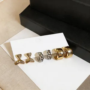 Set of gold fishtail studs, silver twisted hoops, and chunky gold-plated C-shaped earrings.