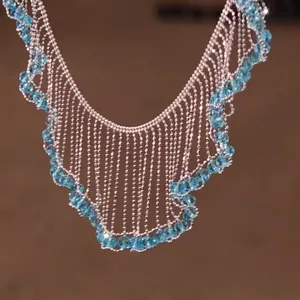 Close-up detail of a silver lace fringe necklace adorned with elegant light blue beads