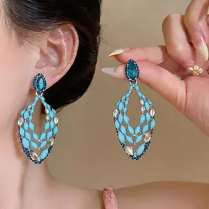 Close-up of elegant blue drop earrings featuring intricate beadwork and rhinestones