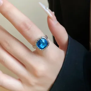 Vista dettagliata di un anello d'argento con una grande gemma blu quadrata sulla mano