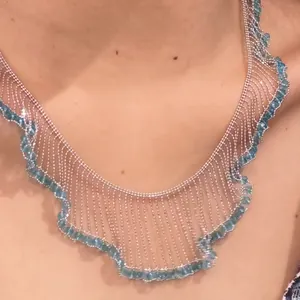 Close-up of a silver French lace fringe necklace with blue beads on a neck