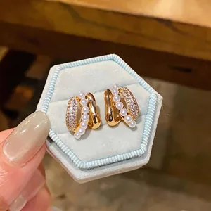 Elegant C-shaped pearl and zircon gold-plated earrings on light blue velvet box