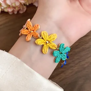 Bohemian style colorful woven raffia flower bracelet worn on wrist for sweet summer vacation look