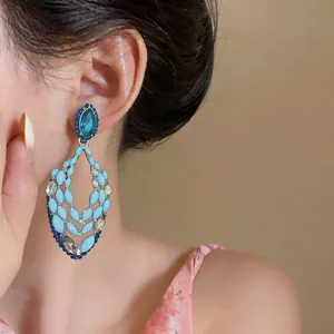 Detail of an oversized light blue enamel and rhinestone hollow teardrop earring on model.