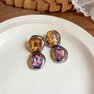 Vintage French style square stud earrings with amber and purple rhinestones on a white plate.