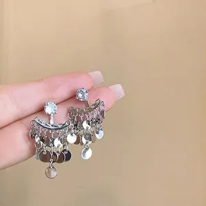 Macro view of silver tassel earrings with crystal studs and layered sequin charms