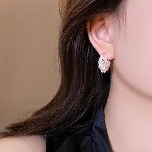 Close-up of elegant floral hoop earrings with pearls and crystals worn by a model