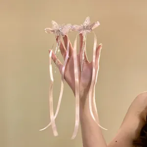 Détail de pinces à cheveux papillon roses avec des pompons élégants et de longs rubans de soie